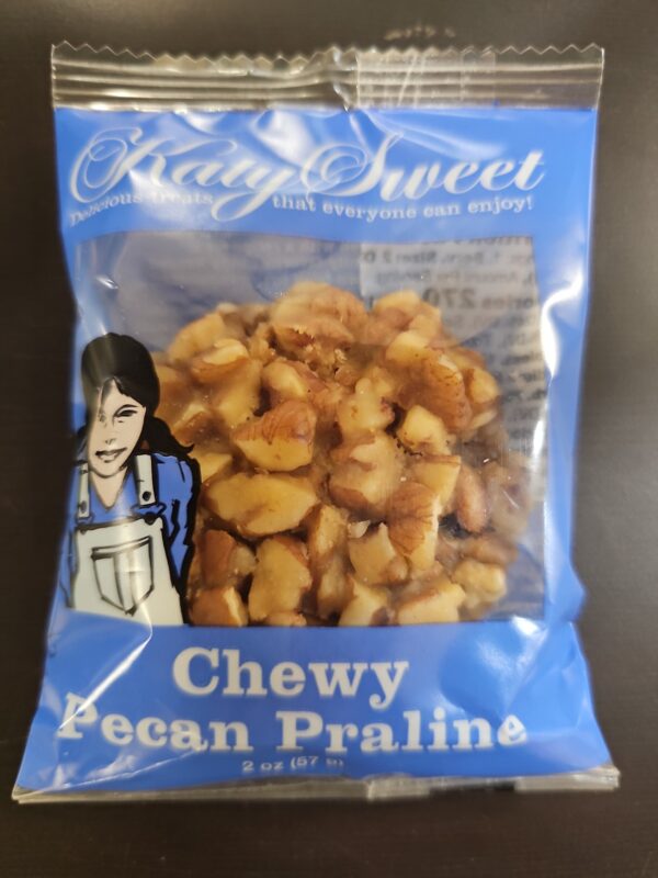 Photo of a Katy Sweet Chew Pecan Praline in a plastic wrapper.